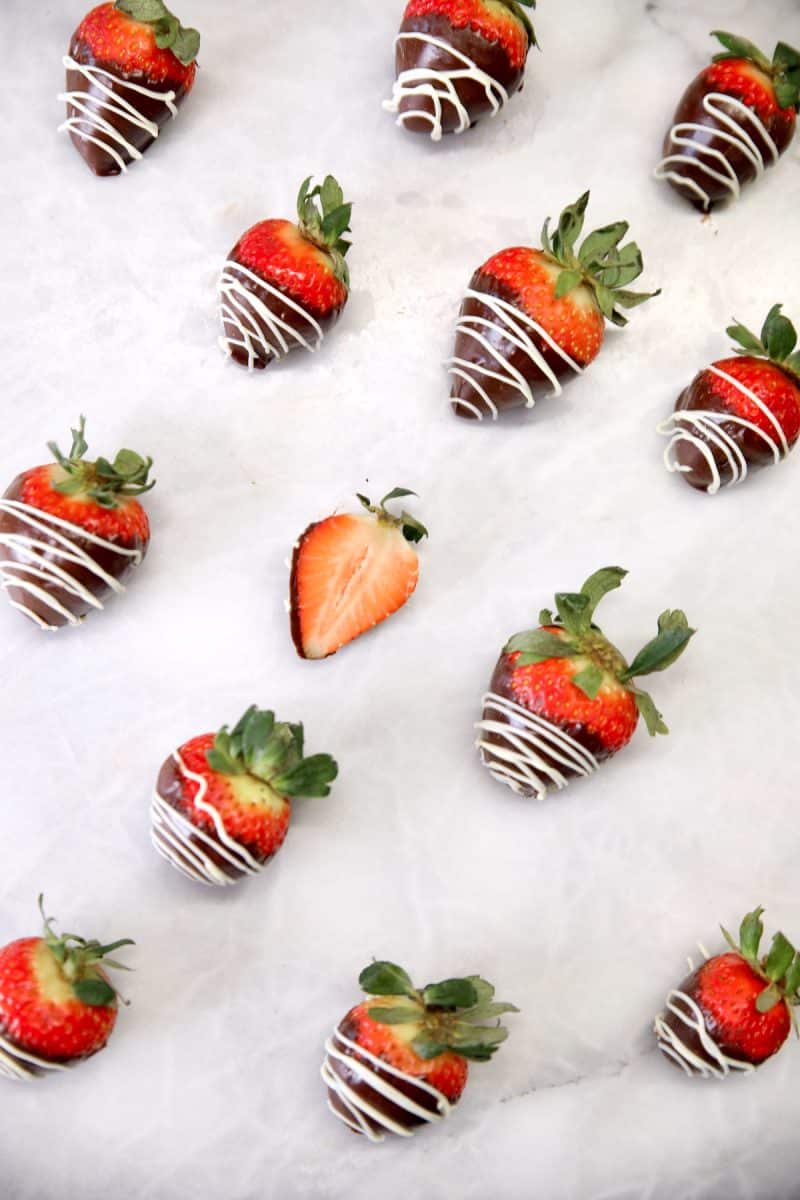 Chocolate covered strawberries on marble. One cut in half in center.