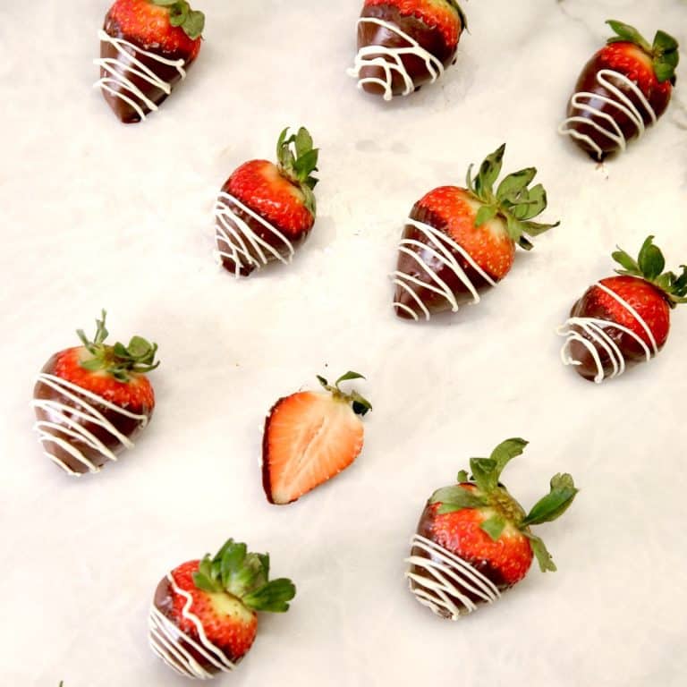 Chocolate covered strawberries with white chocolate drizzle. One cut in half.