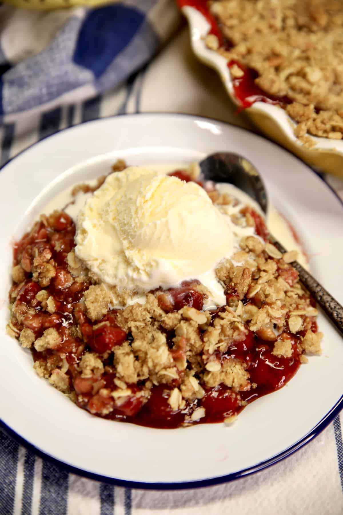 Easy cherry crisp with vanilla ice cream on a plate.