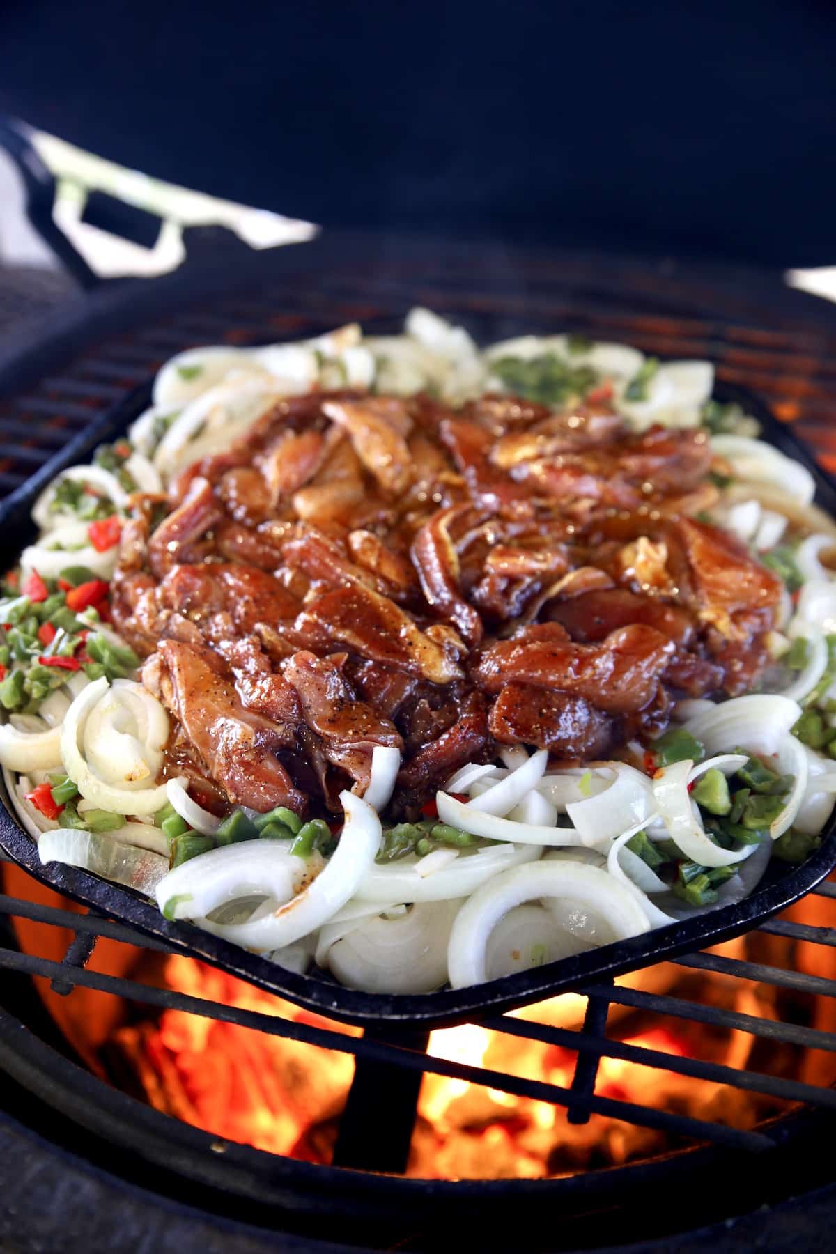 Cooking chicken fajitas with onions and peppers on a grill.