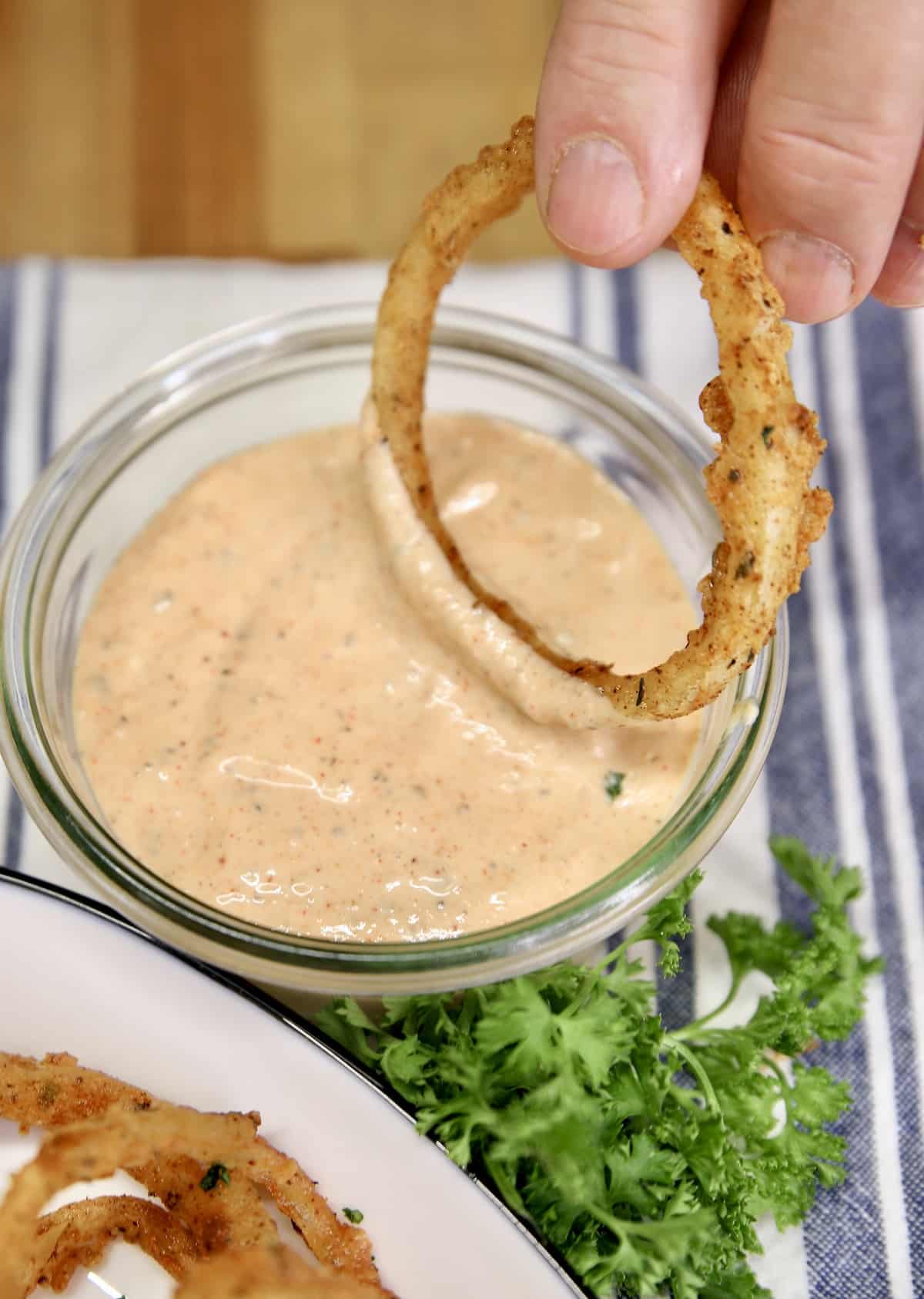 Dipping onion ring in blooming onion sauce.