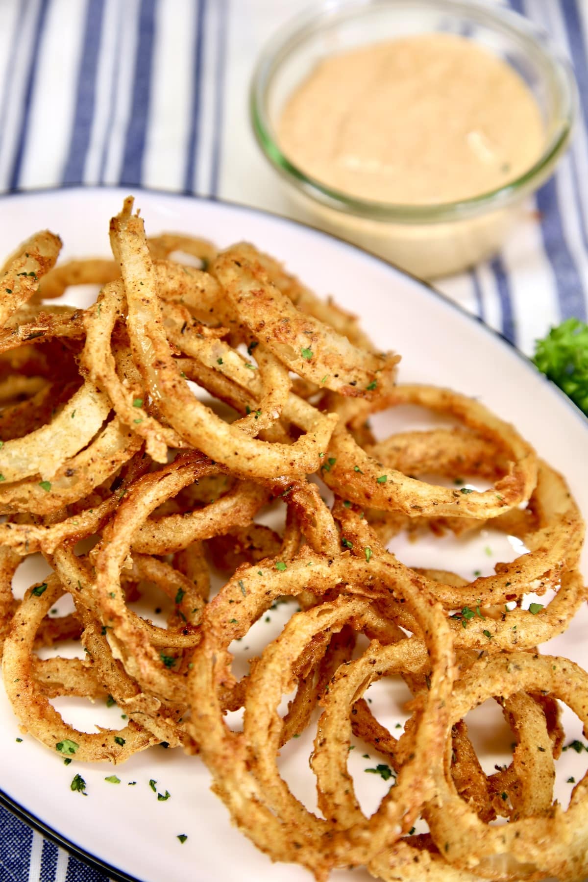 Platter of crispy onion rings. Fried onion rings on a platter with bowl of dipping sauce.