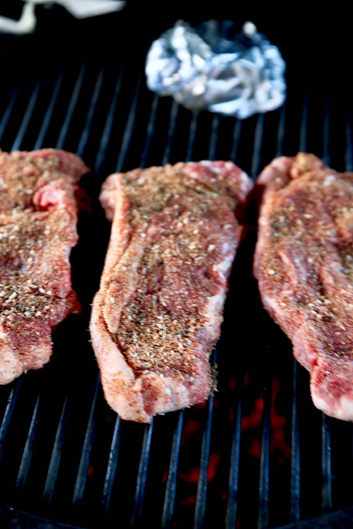 Grilling 3 NY strip steaks.