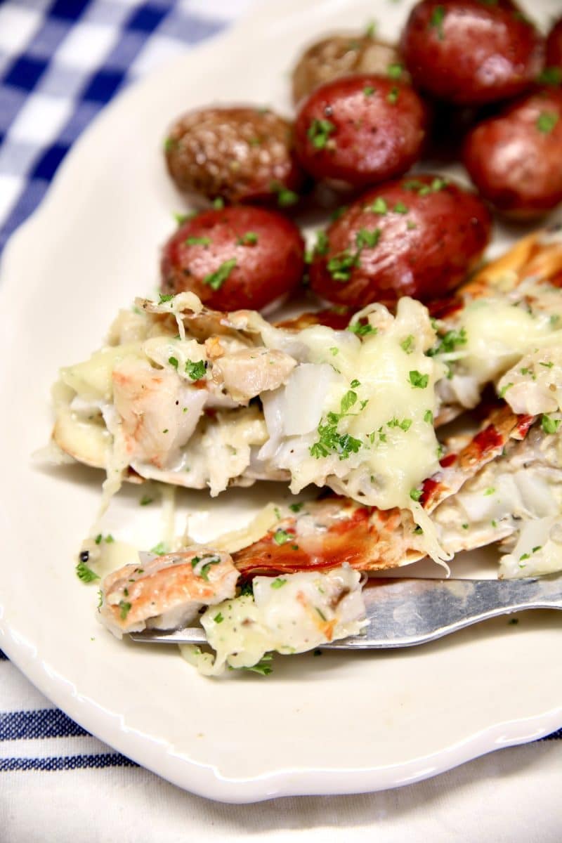 Lobster Thermidor on a plate with bite on fork and small red potatoes.