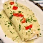 Smothered chicken burrito topped with diced tomatoes and cilantro.