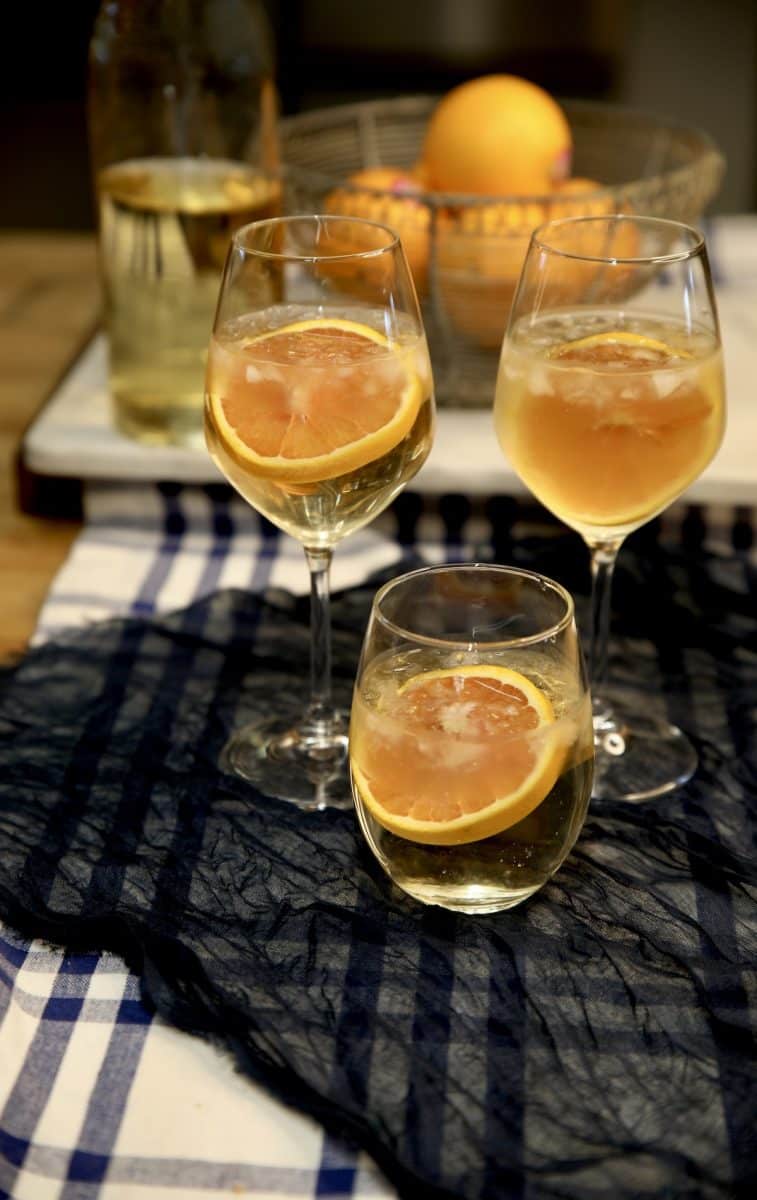 3 wine spritzers with orange garnish.
