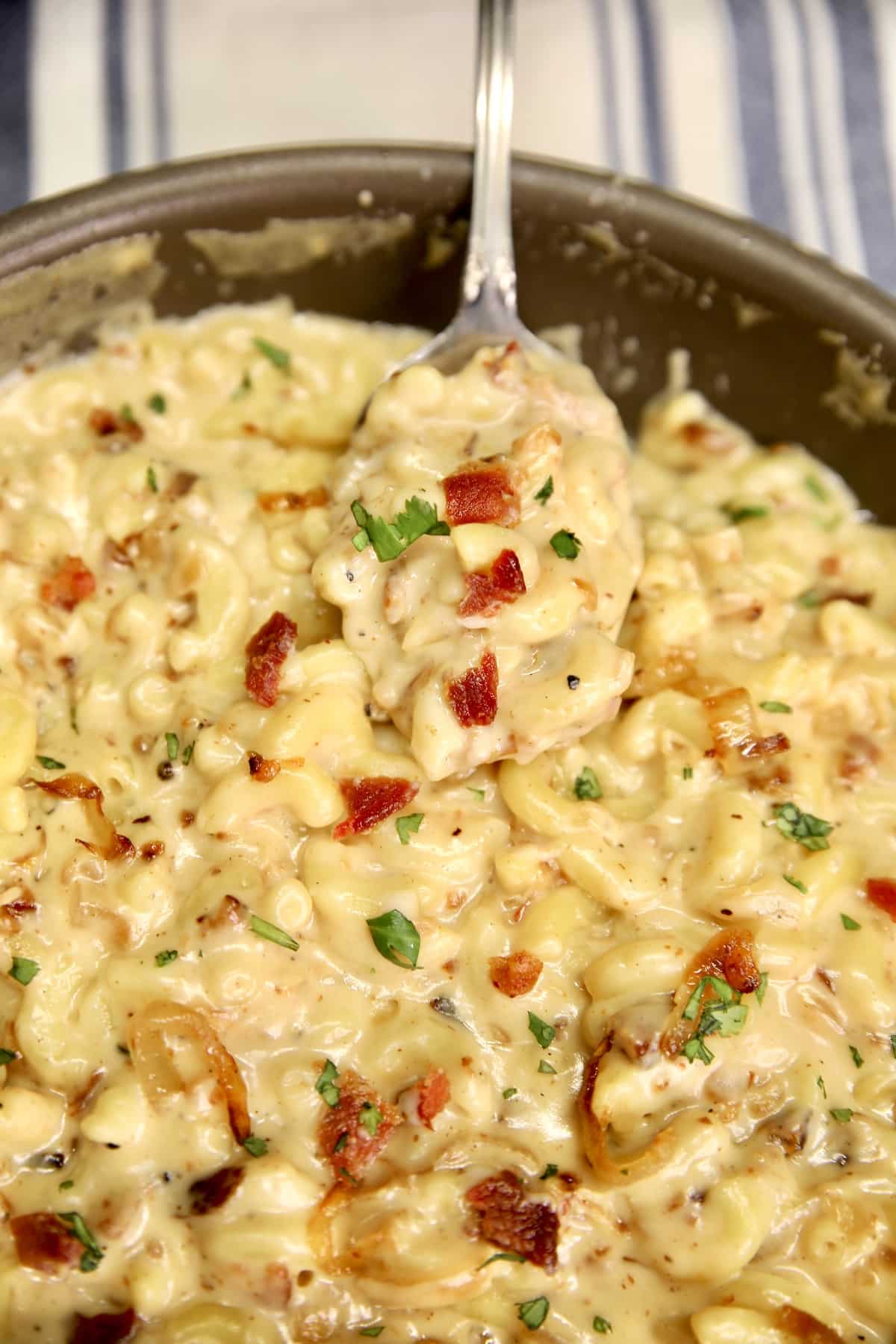 Spoonful of mac and cheese with bacon and onions.