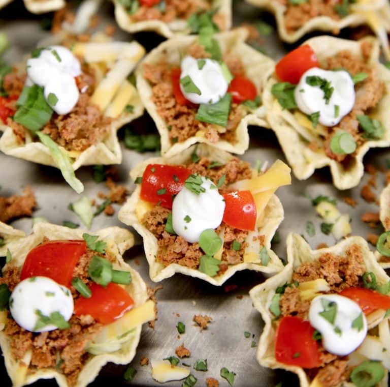 Taco bites appetizer with tomatoes and sour cream.