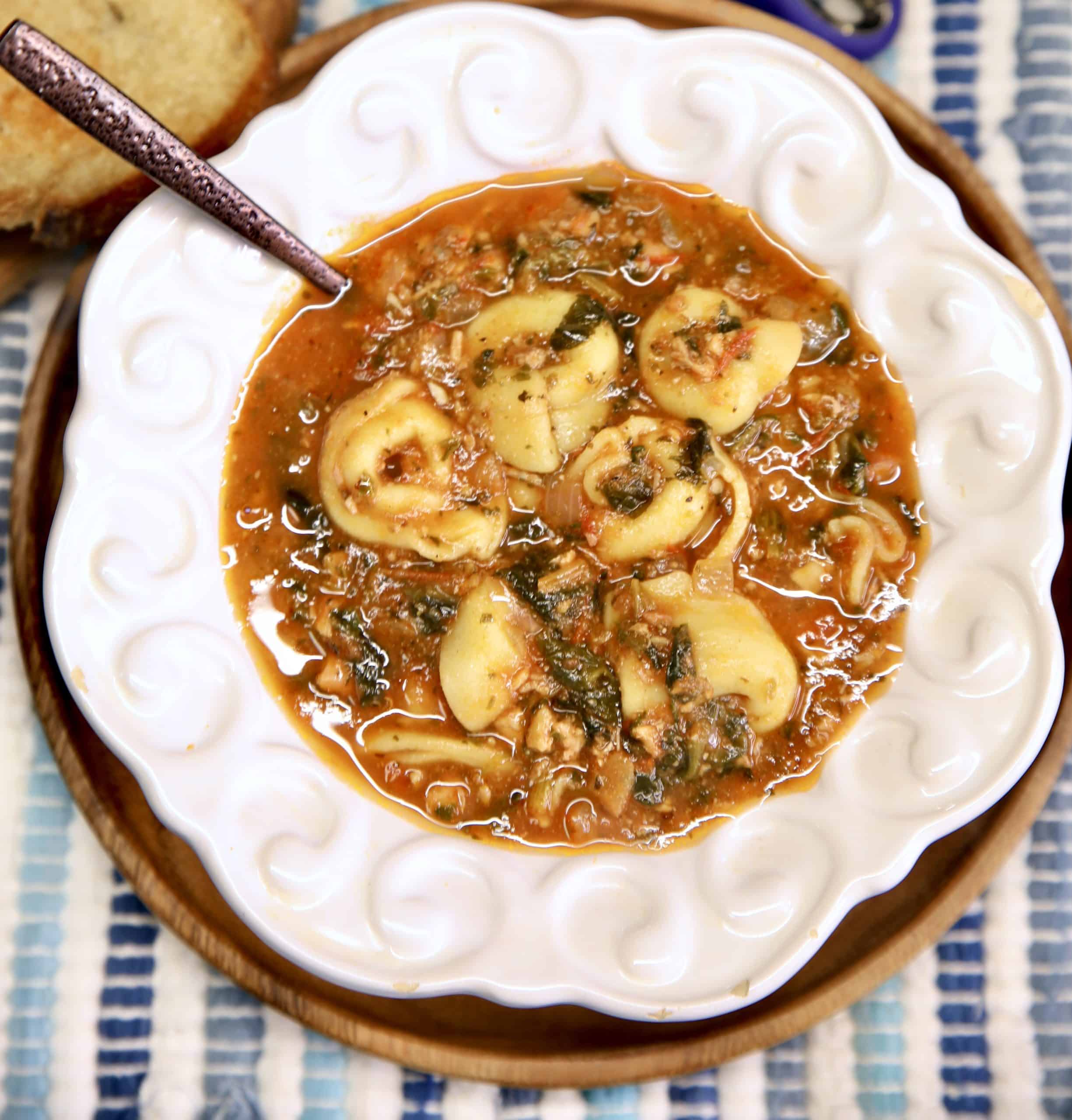 Bowl of tomato tortellini soup with spoon.