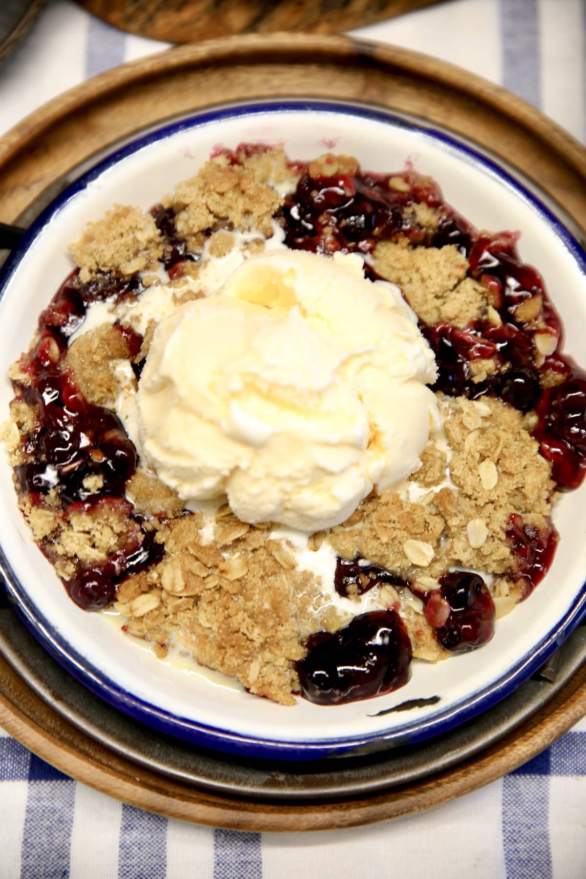 Closeup of plate with blueberry pie filling and vanilla ice cream.