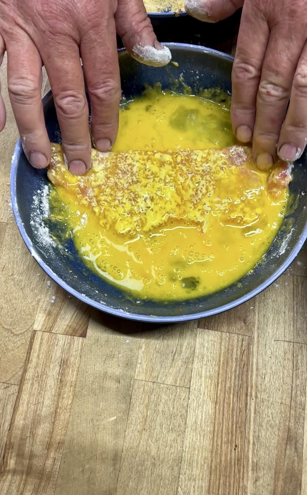 Dipping pork cutlets in egg.