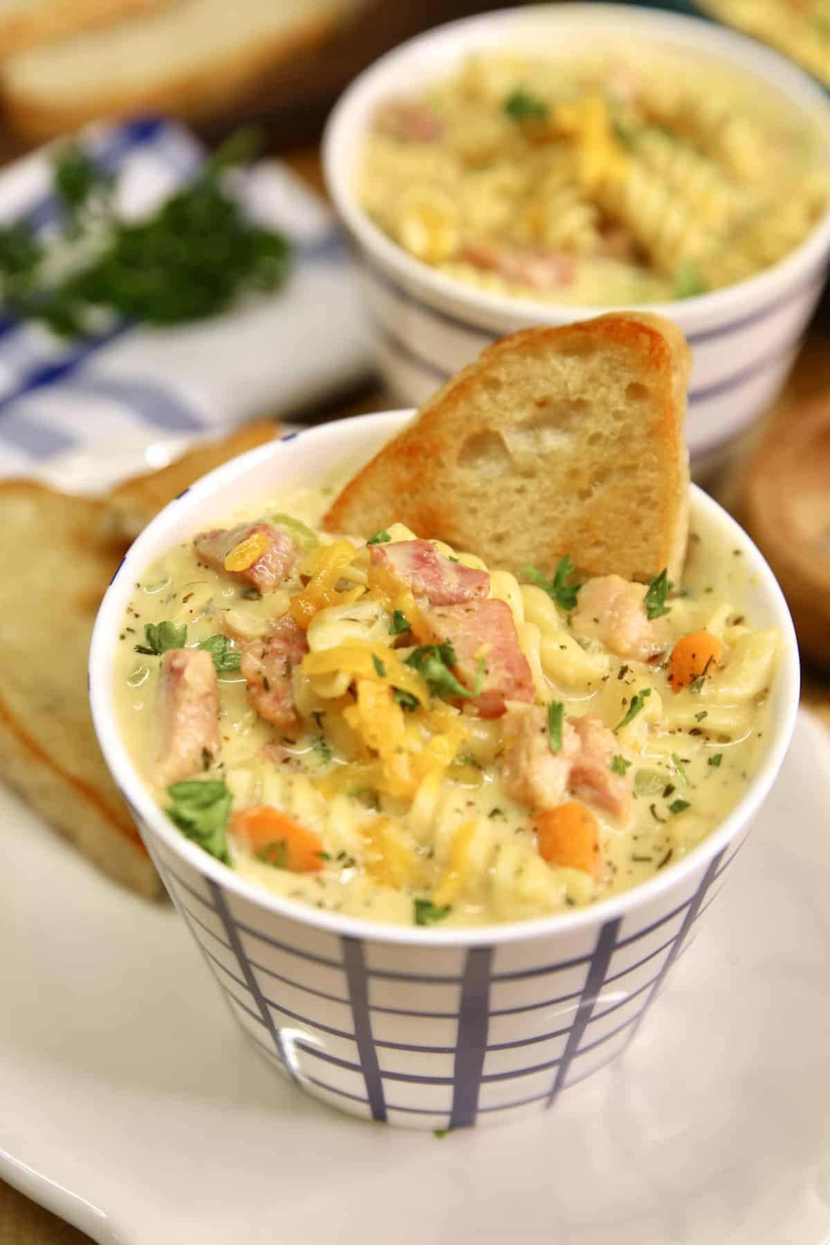 Ham soup in a soup mug with slice of toasted bread.