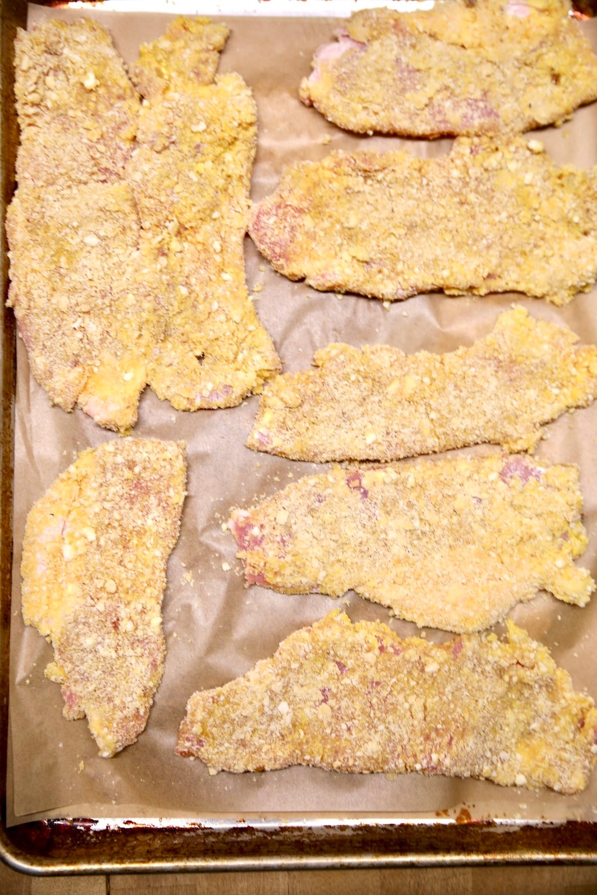 Breaded pork cutlets on a baking sheet.