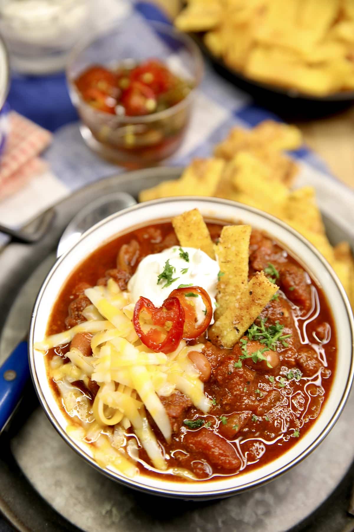 Bowl of chili with cheese, sour cream and candied jalapenos.