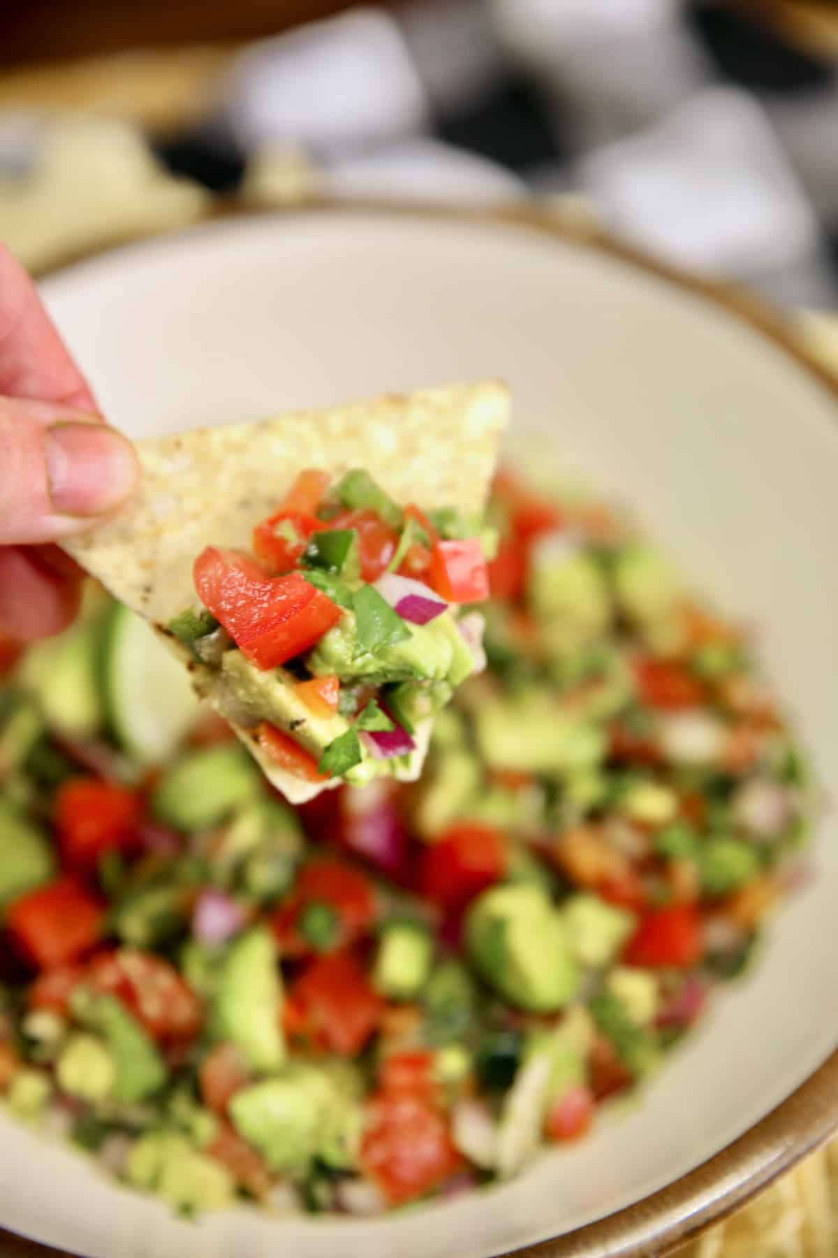 Chip dipping into avocado salsa.