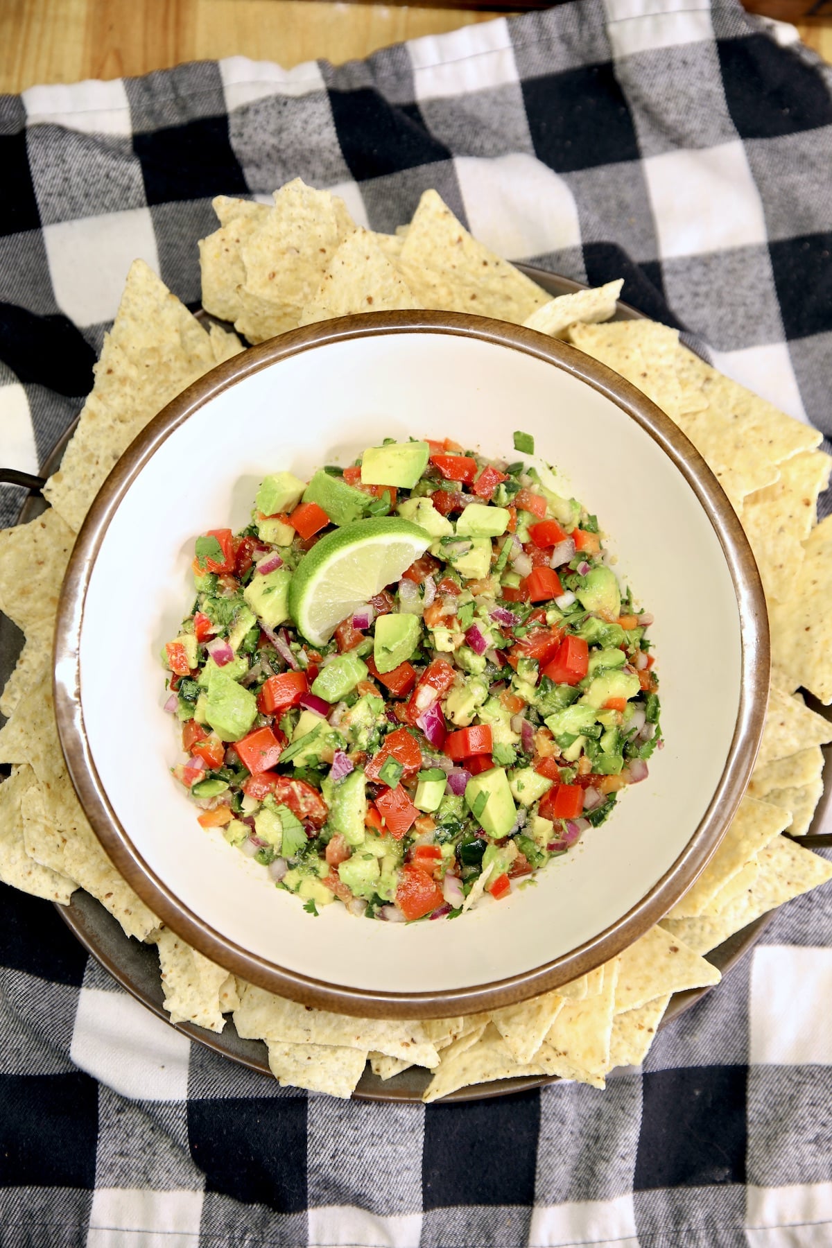 Avocado Salsa with chips on a black and white check napkin.
