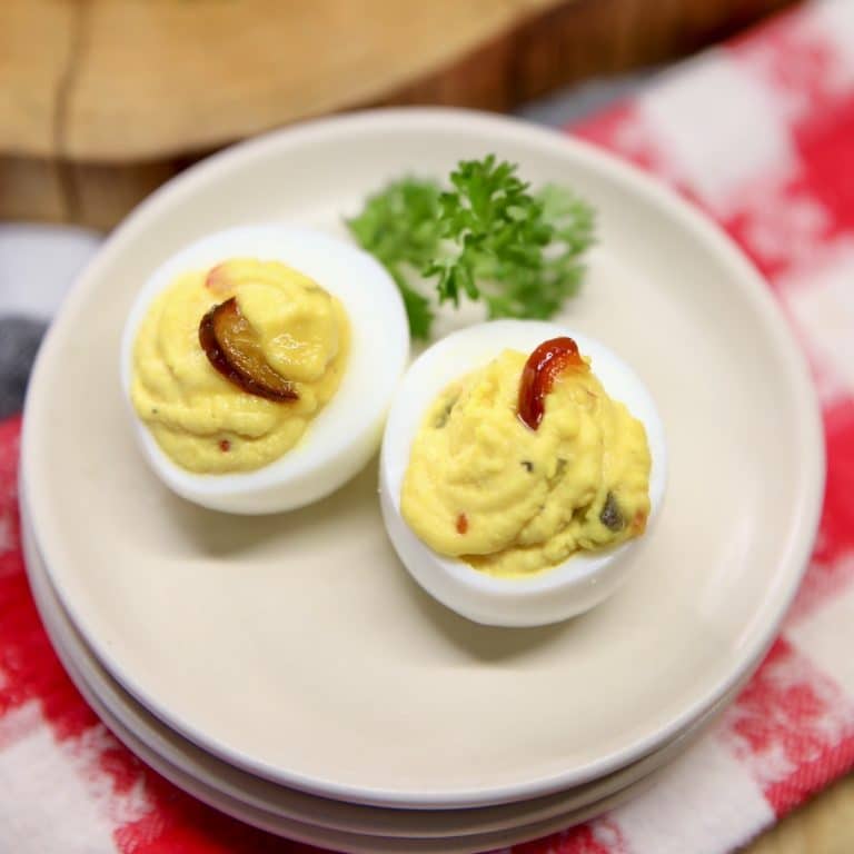 2 deviled eggs on a small plate with parsley.
