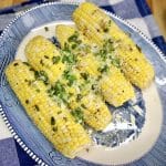 Platter with 4 corn on the cob topped with green onions.