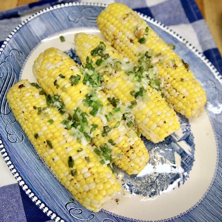 Platter with 4 corn on the cob topped with green onions.