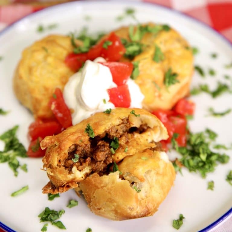 Plate with 3 taco bombs, sour cream, diced tomatoes, cilantro.