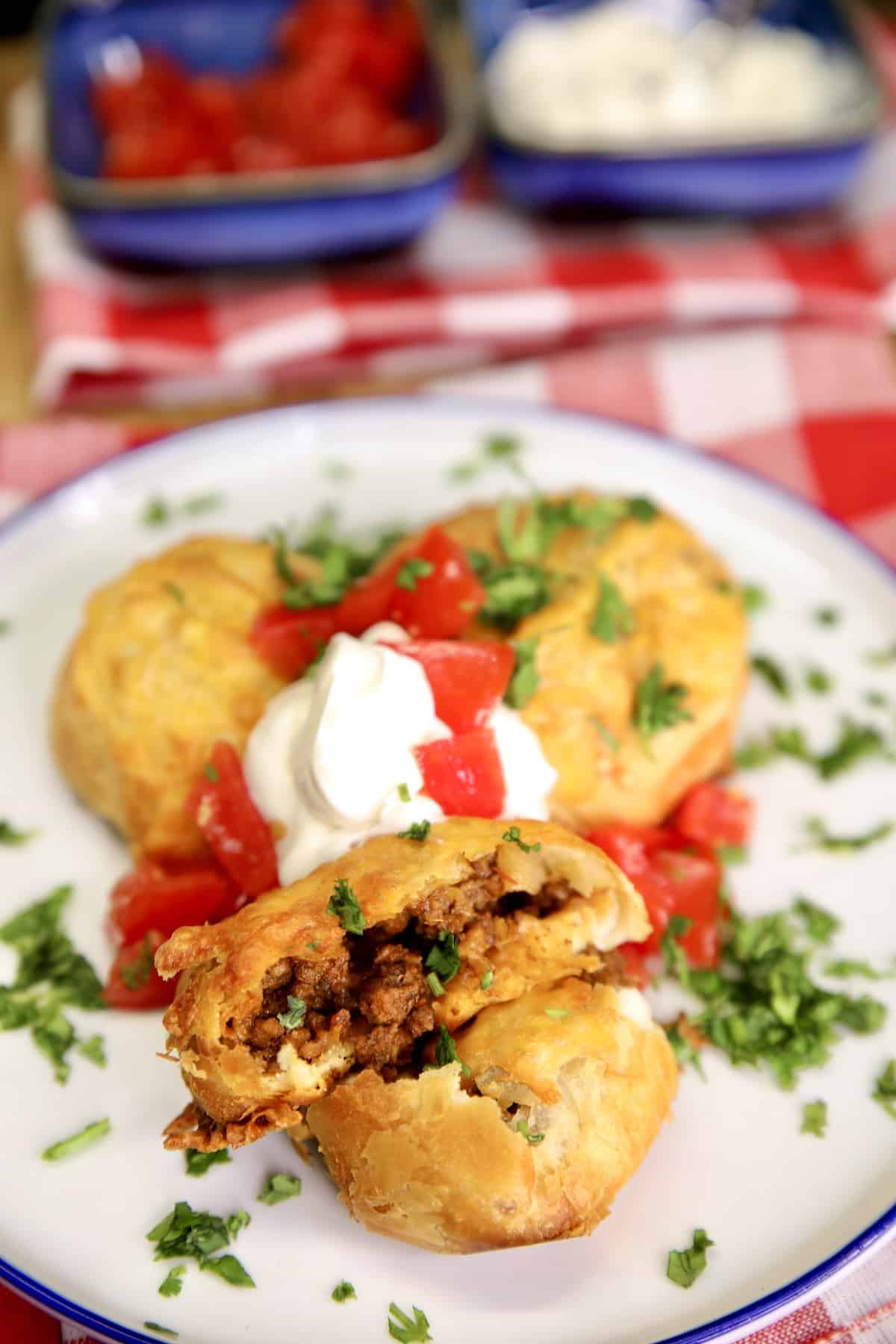 Cheesy taco bombs plated with sour cream and tomato garnish.