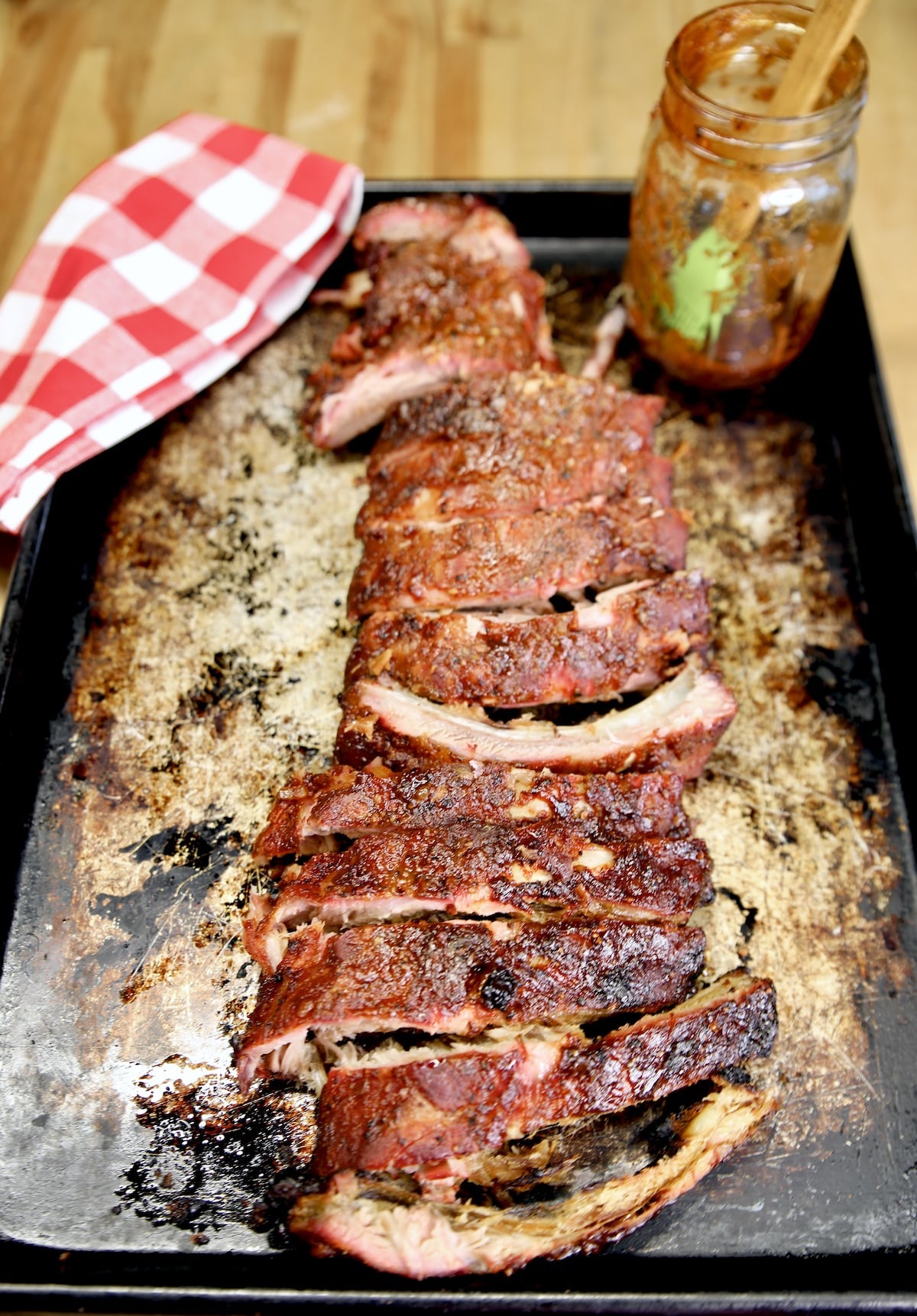 Sheet pan with sliced baby back ribs, jar of sauce.