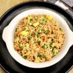Bowl of fried rice with carrots, peas, eggs.