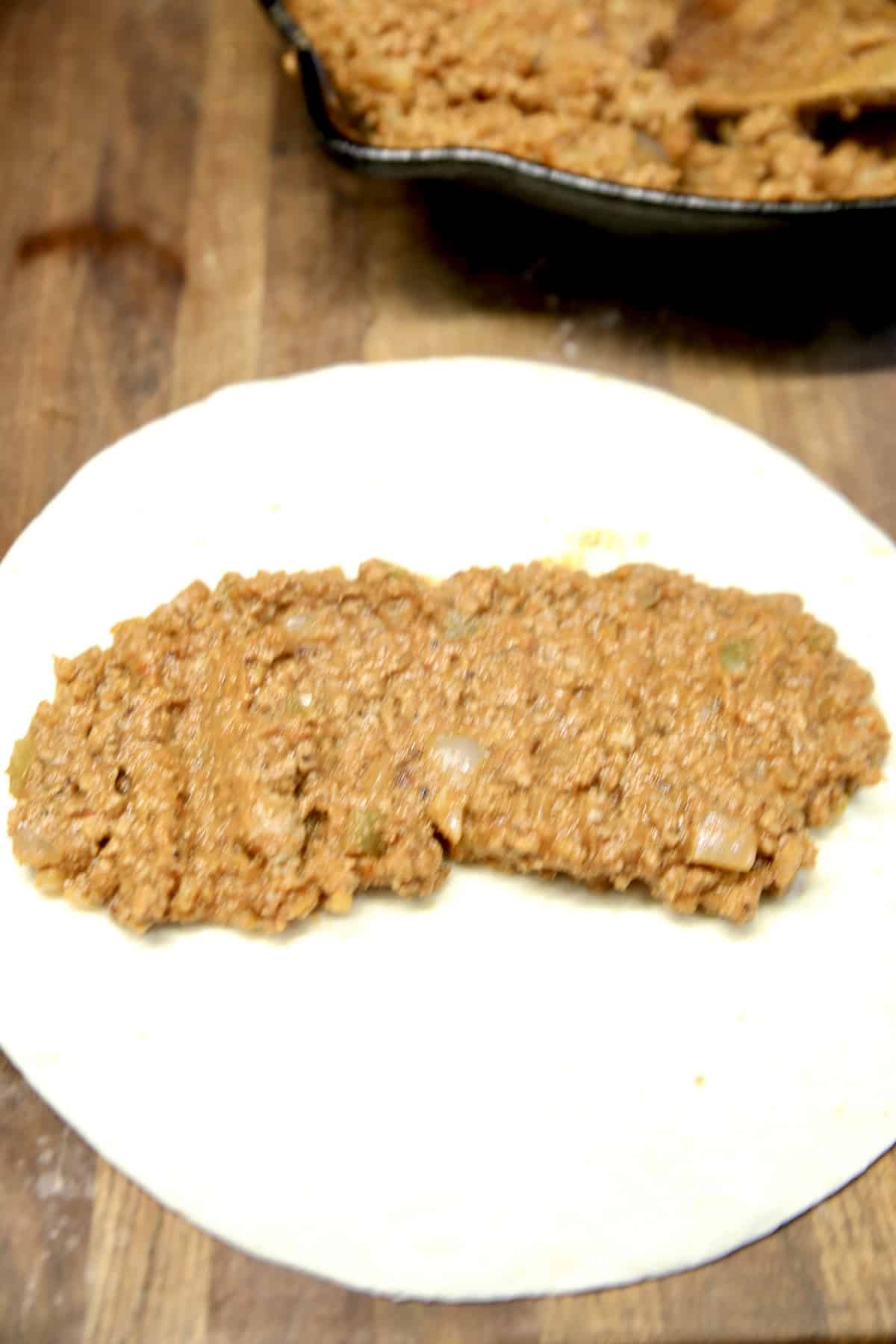 Filling flour tortilla with beef and bean mixture.