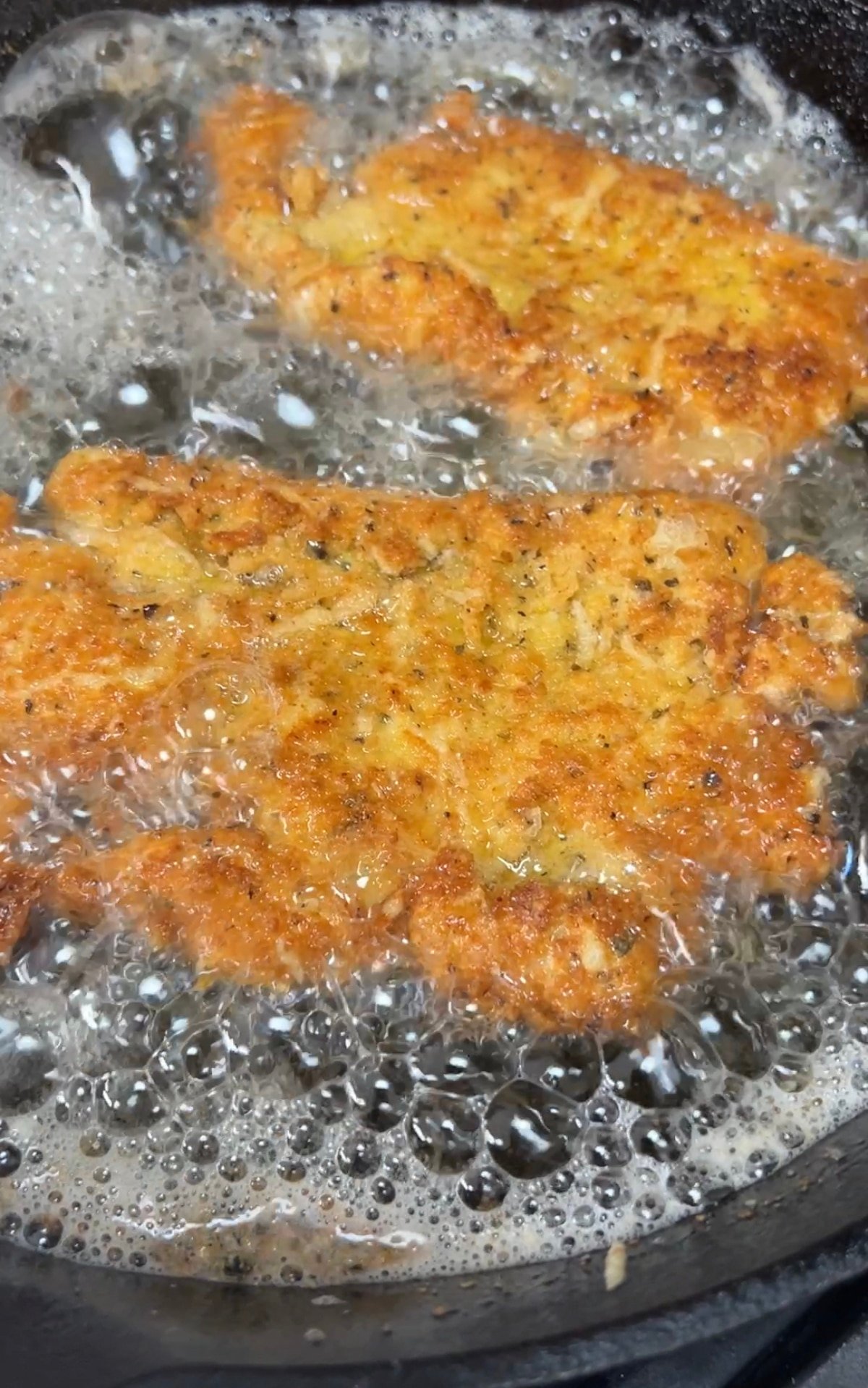 Crispy fried parmesan chicken. Frying chicken cutlets in a skillet.