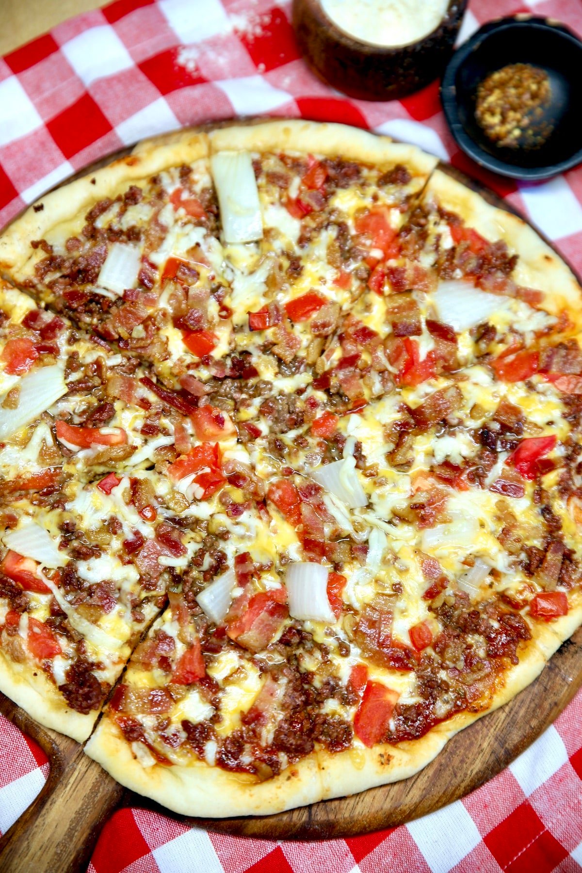 Bacon Cheeseburger Pizza on a pizza peel, red check napkin.