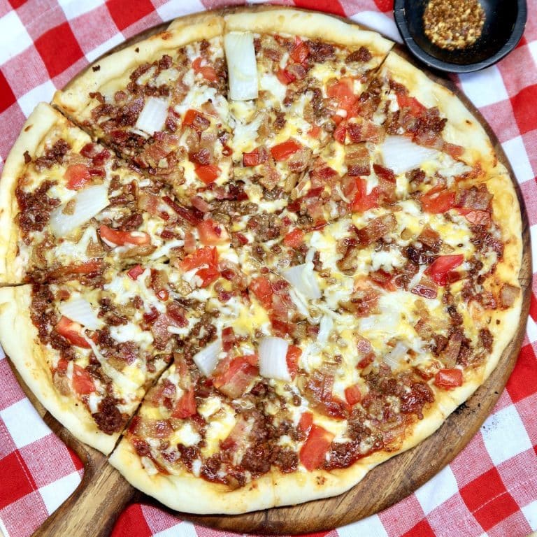Bacon Cheeseburger Pizza on a pizza peel, red check napkin.