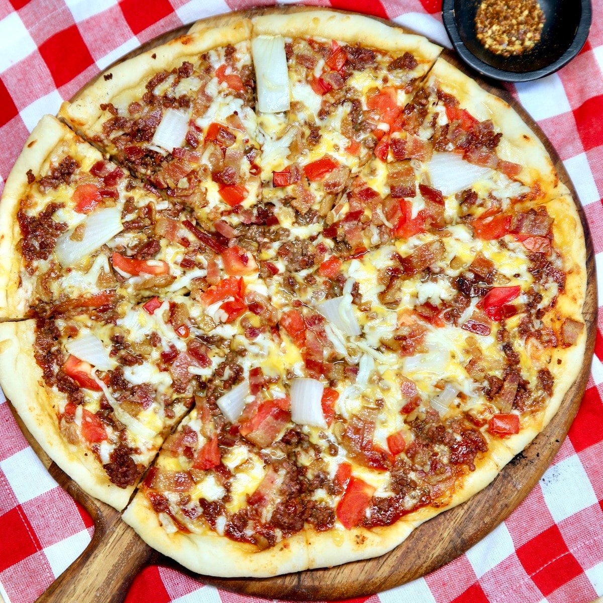 Bacon Cheeseburger Pizza on a pizza peel, red check napkin.