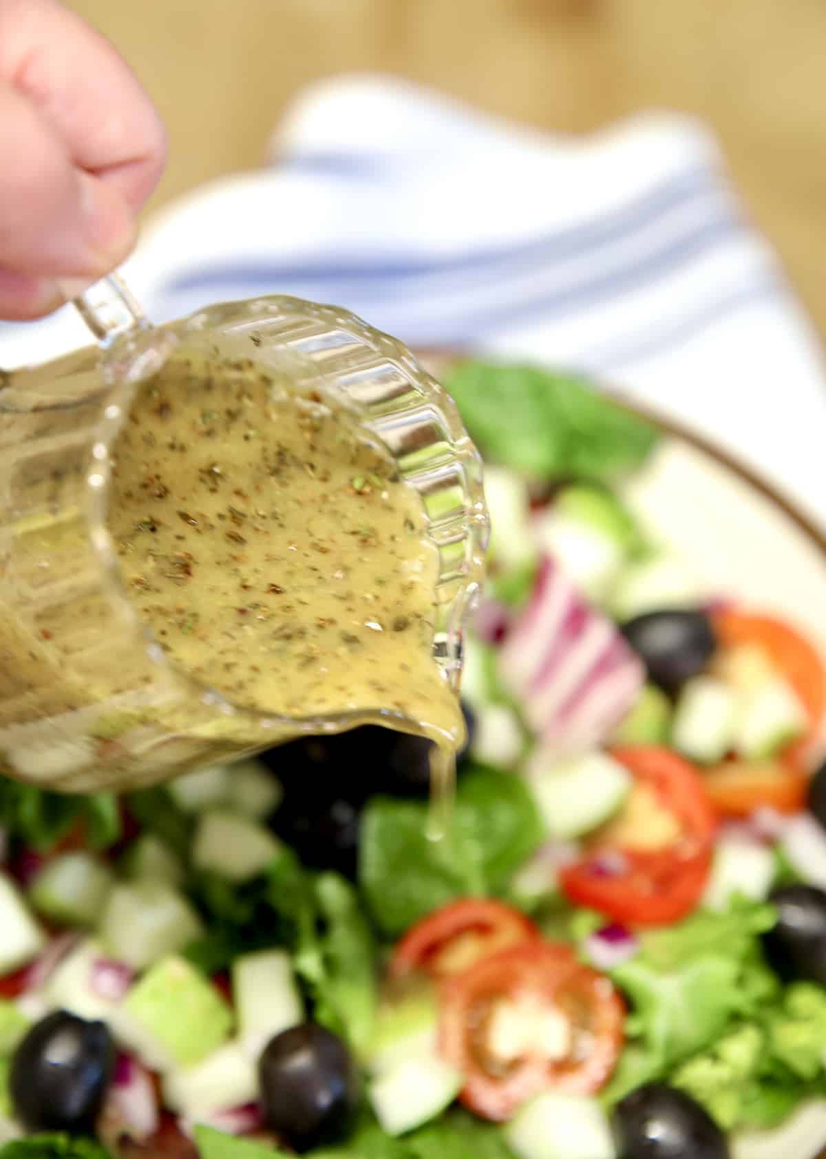 Pouring Italian dressing on salad.