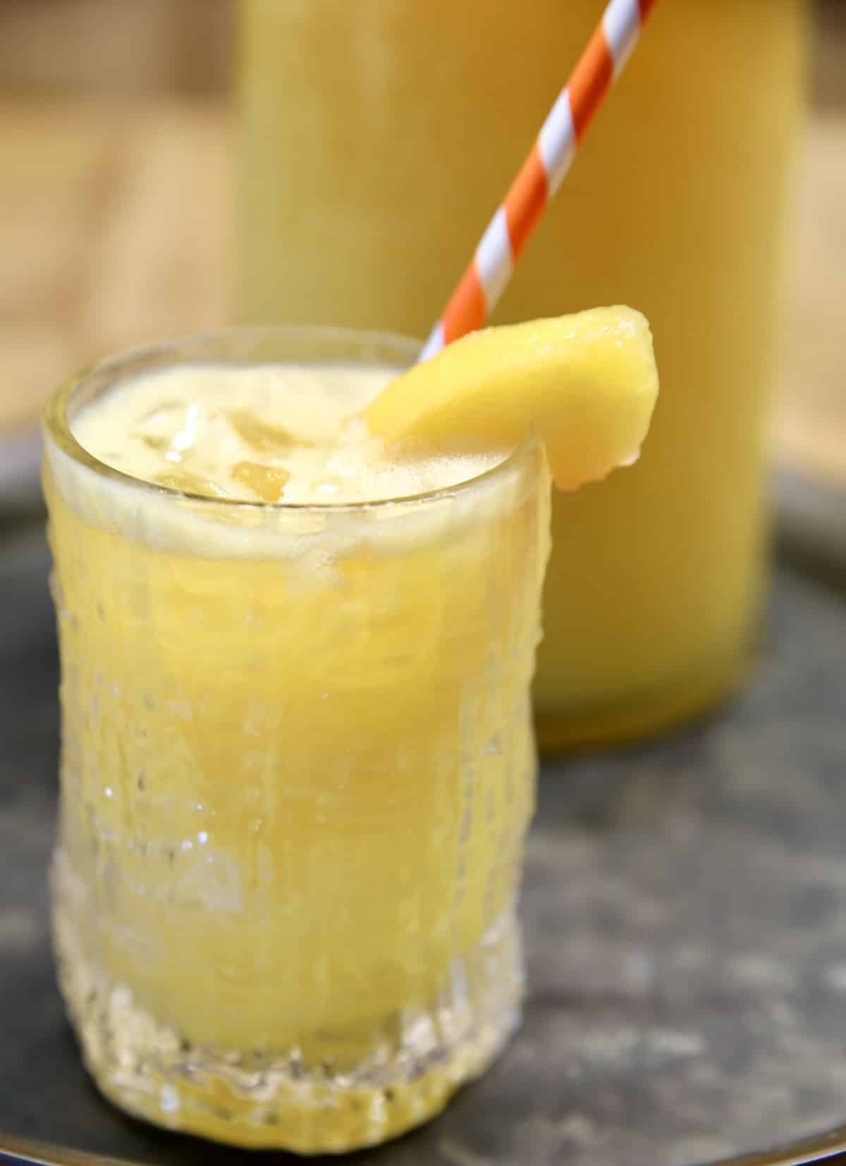 Moscato punch with peaches and mango. Peach Mango Moscato Punch in a glass with orange stripe straw.