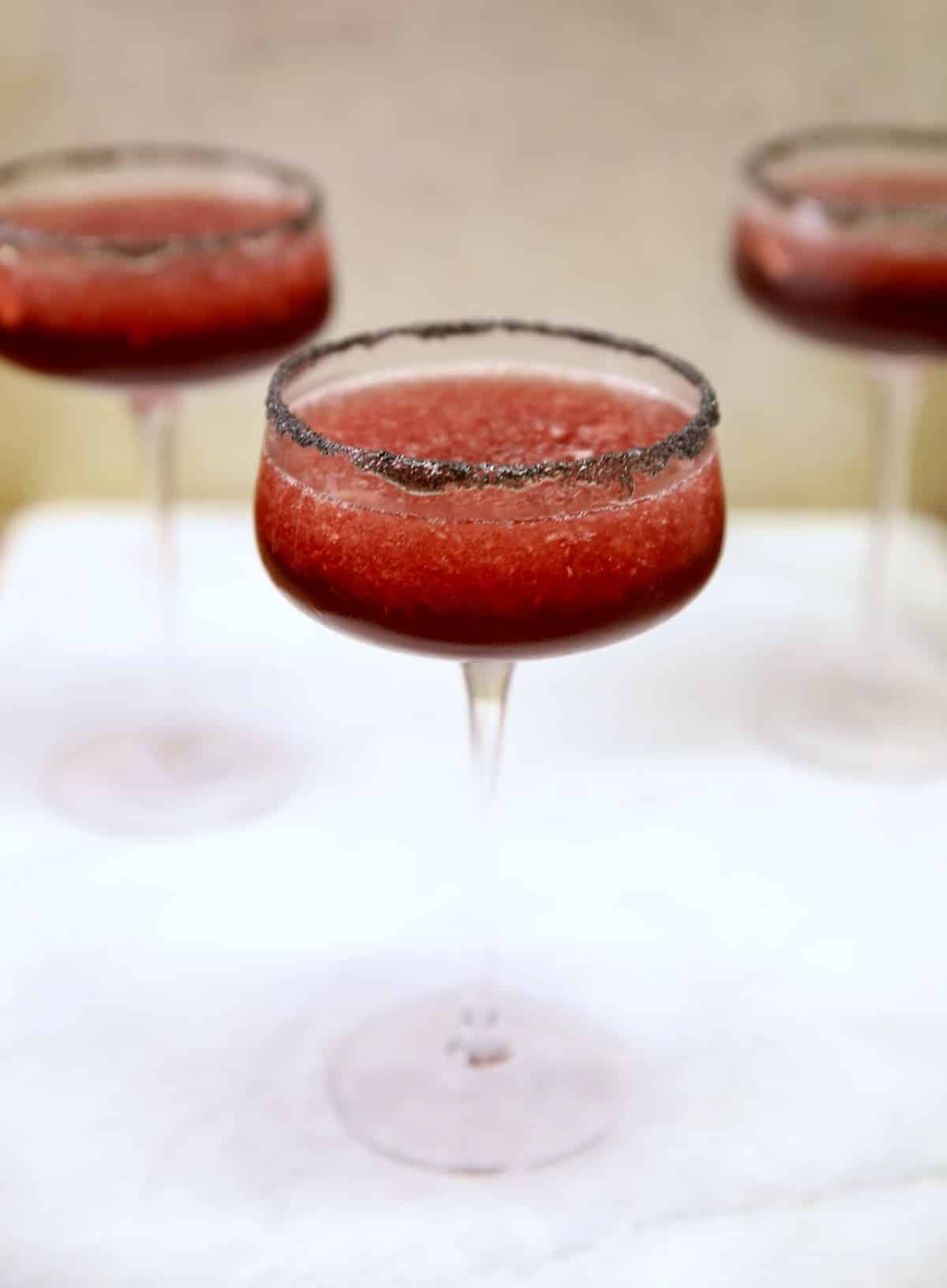 Black cherry margaritas in 3 coupe glasses.