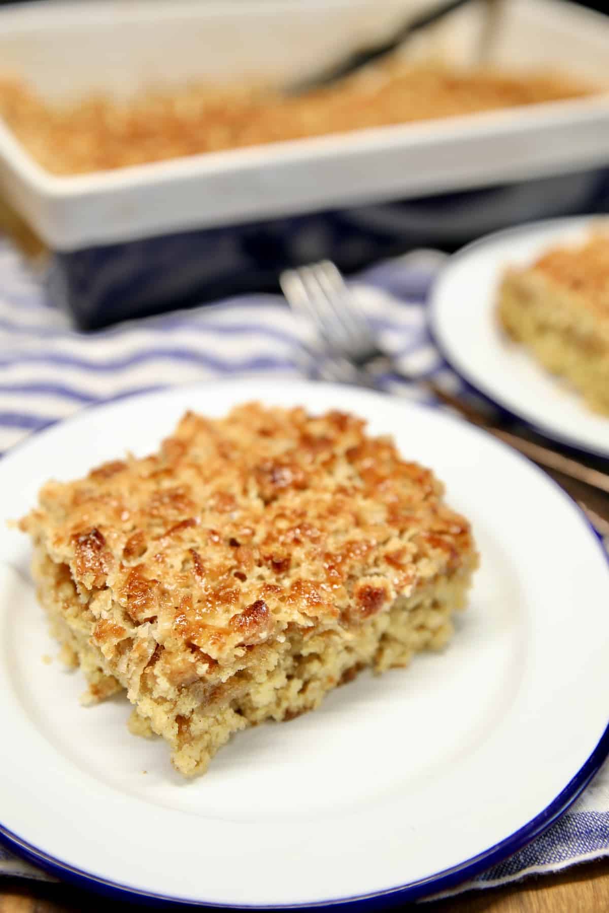 Slice of oatmeal cake on a plate, cake pan in background.