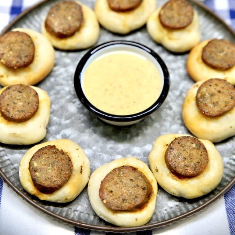 Smoked sausage bites with pizza dough and mustard sauce on a platter.