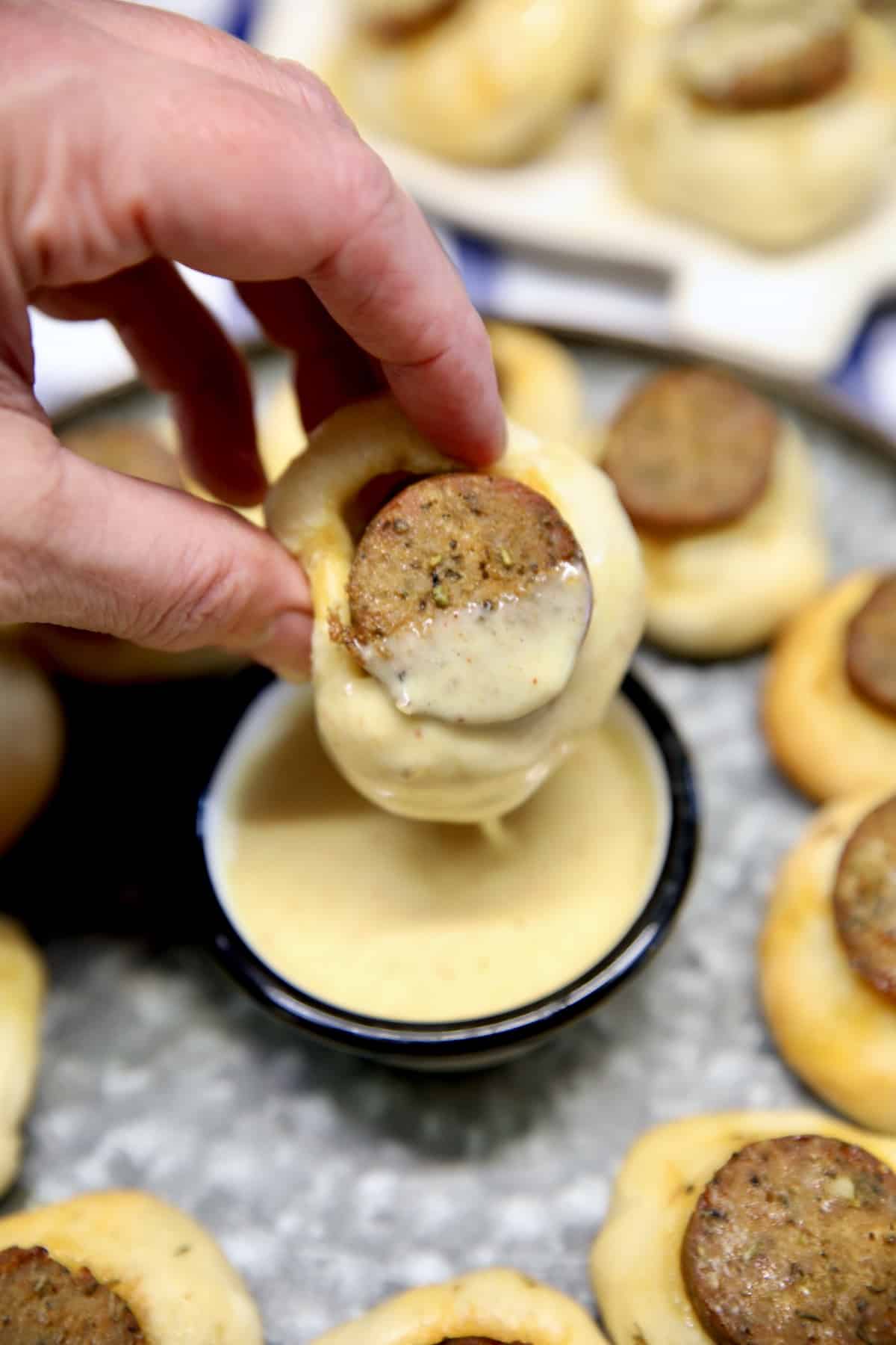 Dipping smoked sausage bite into honey mustard.