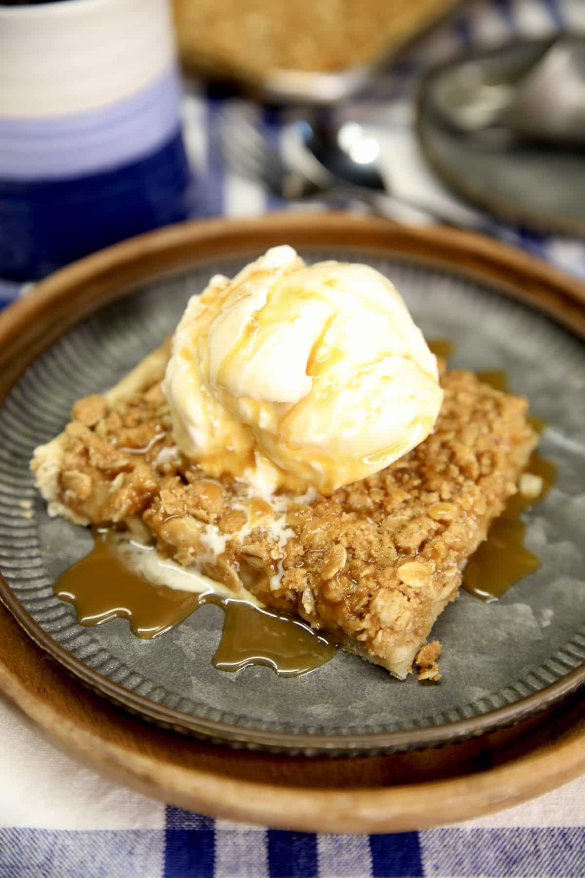 Slice of apple pie with vanilla ice cream and caramel sauce.