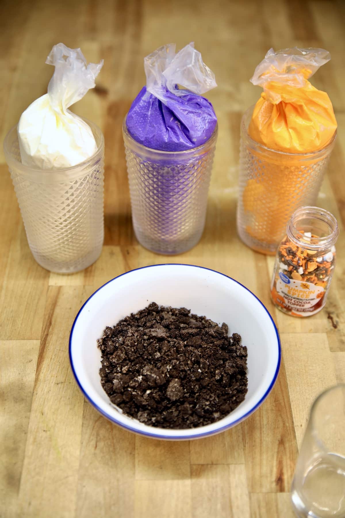No bake cheesecake in piping bags, bowl of crushed Oreos.