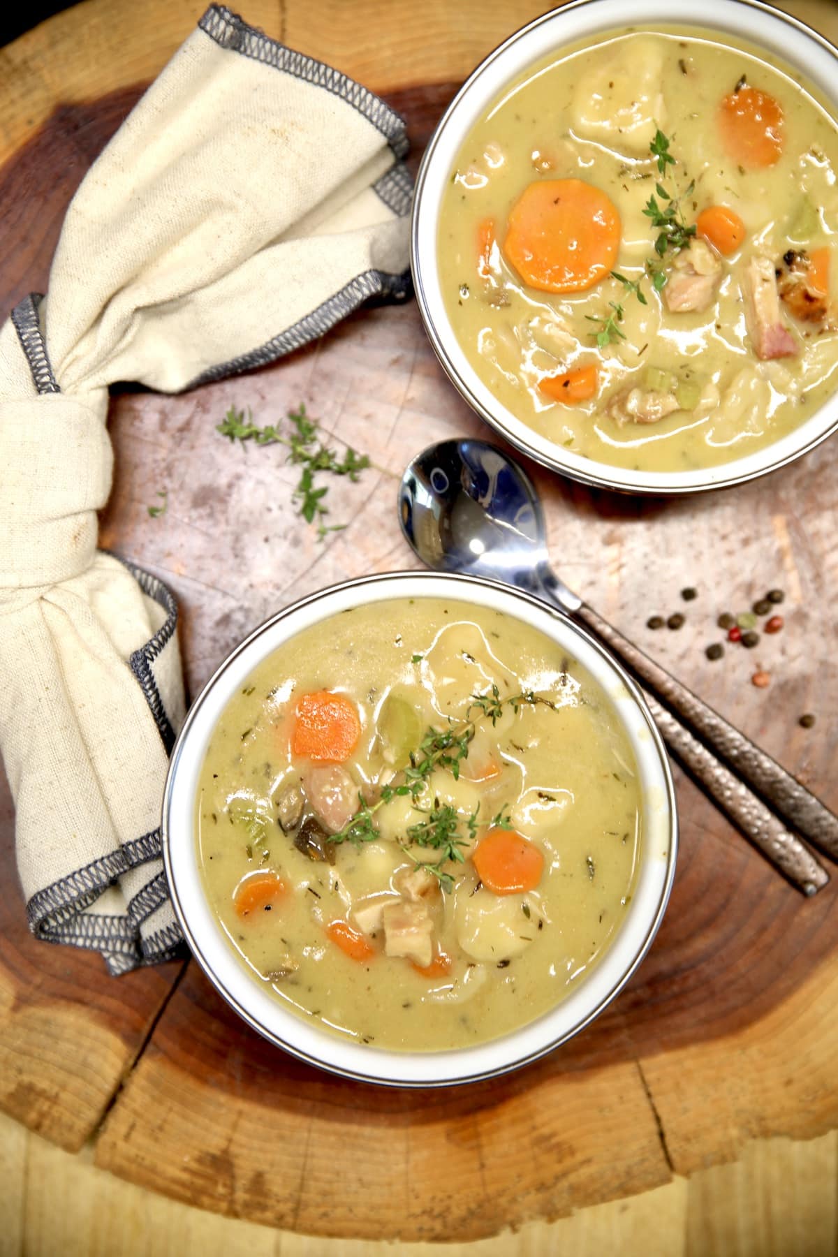 2 bowls of chicken and dumplings with spoon and napkin.