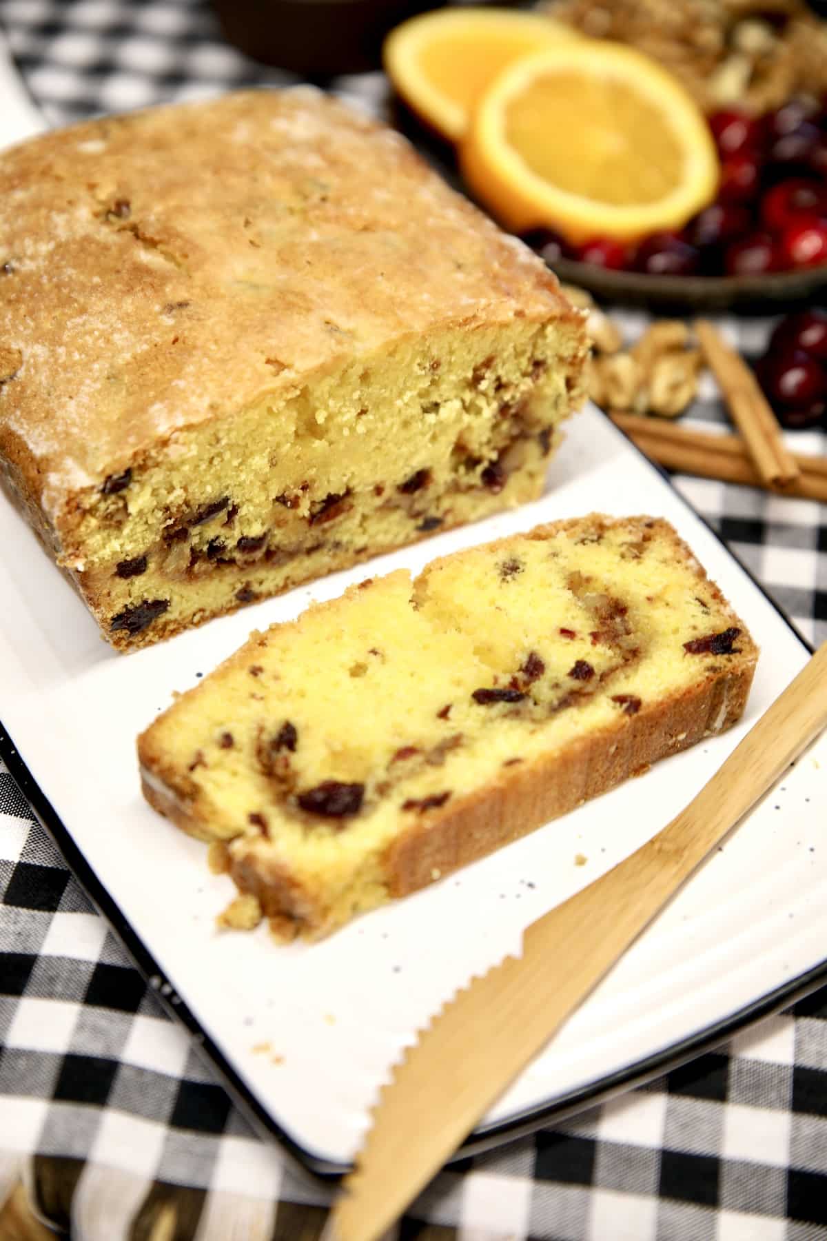 Cranberry orange loaf cake, sliced on a board, wood knife.