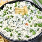 Bowl of spinach dip with 2 crackers.