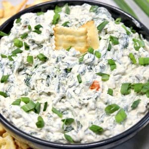 Bowl of spinach dip with 2 crackers.