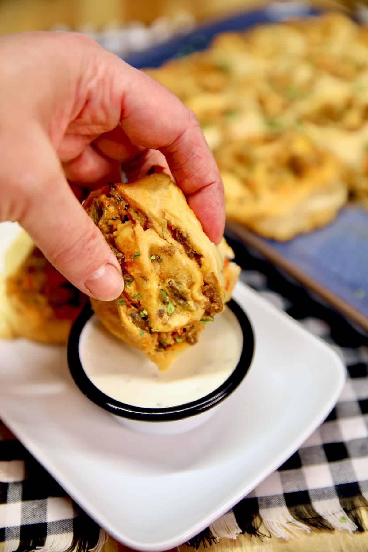 Sausage pinwheel dipping into ranch dressing.