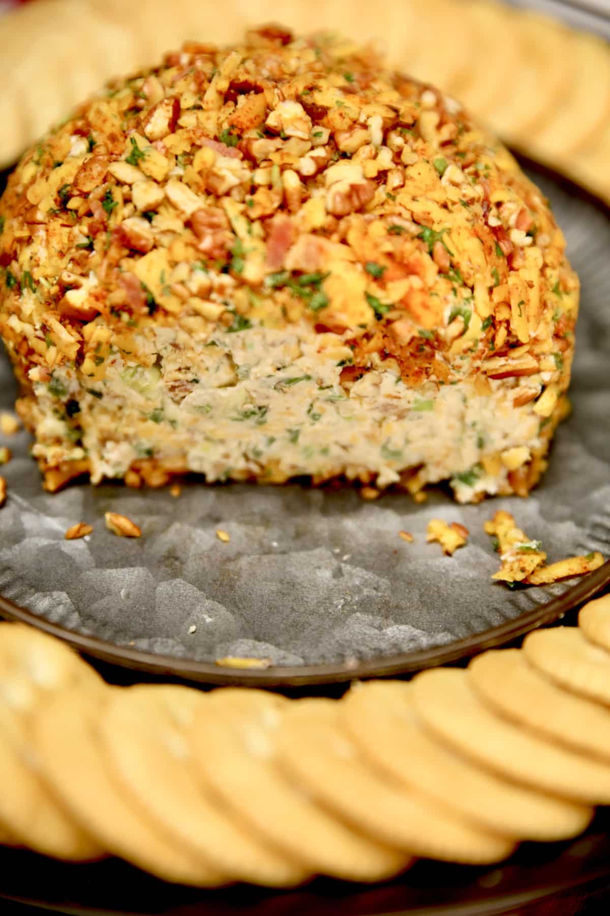 Cheese ball on a platter with crackers, inside showing.