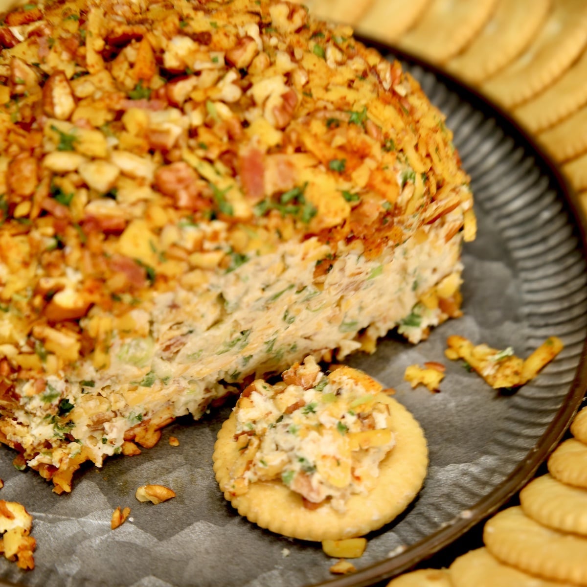 Jalapeno popper cheese ball on a platter with crackers.