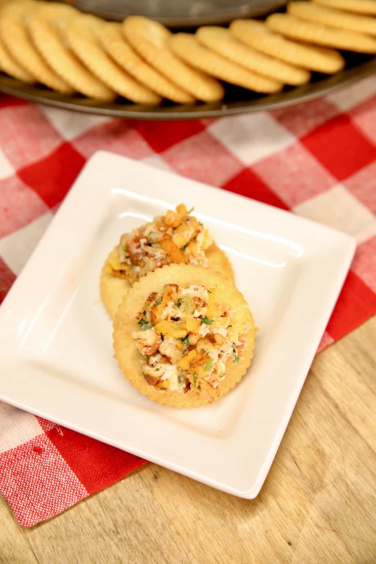 Crackers with jalapeno popper cheese ball on a small square plate.