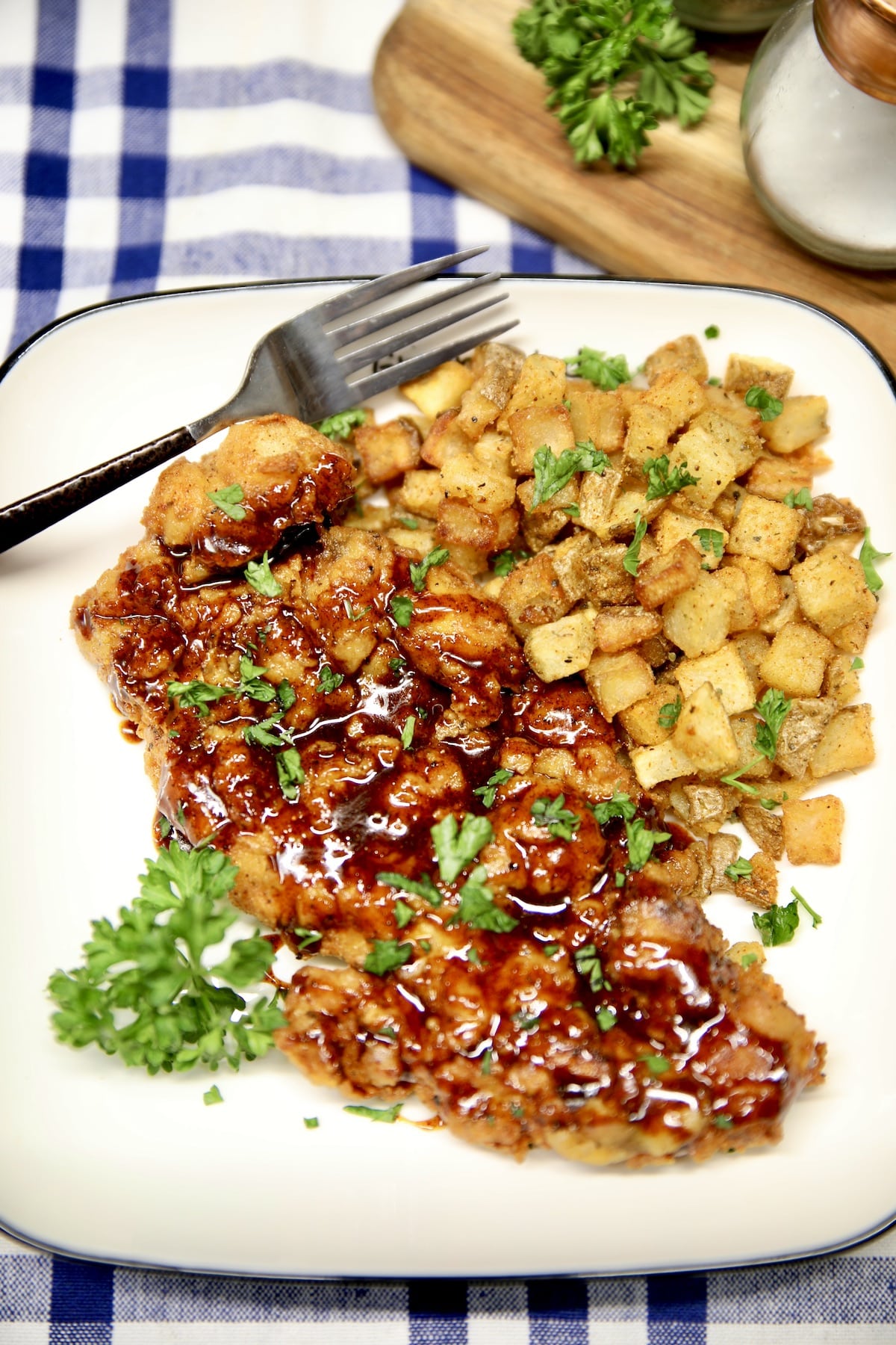 Chipotle honey chicken on a plate with cubed potatoes.