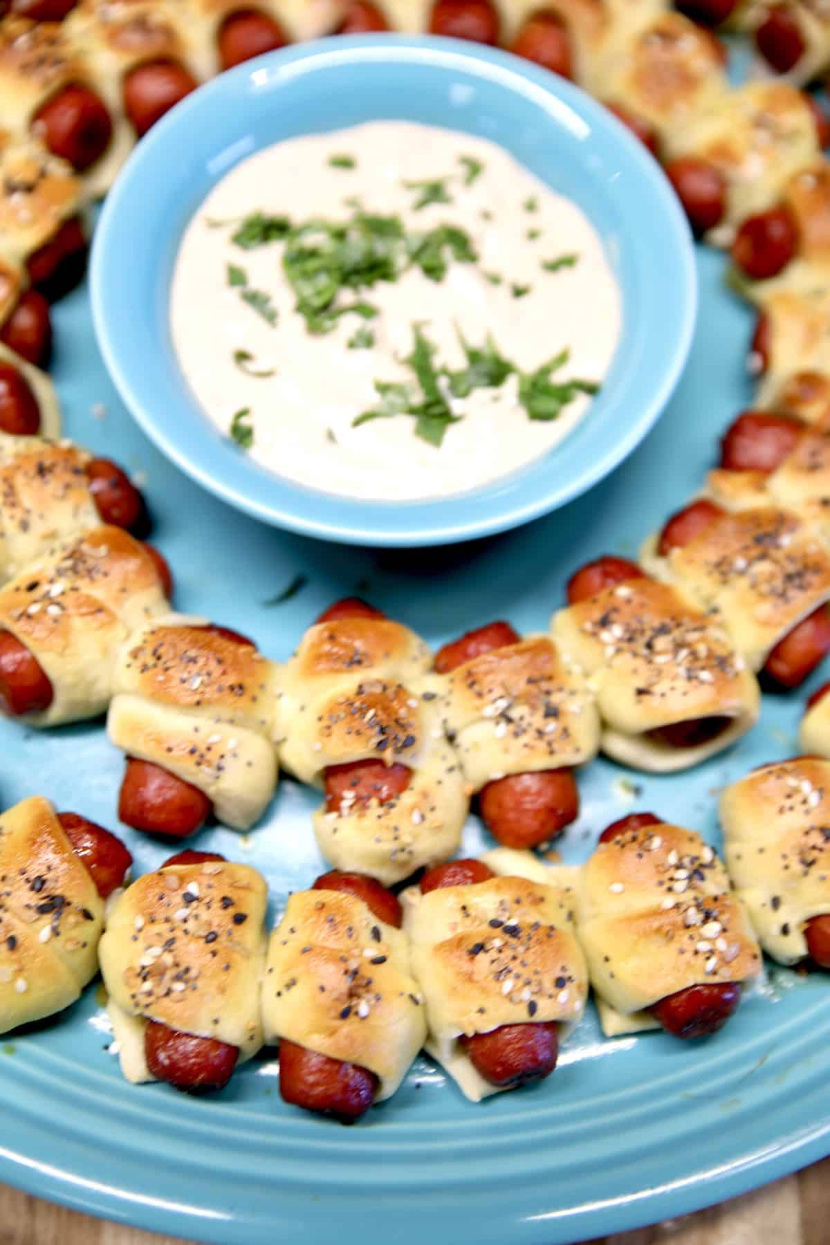 Mini pigs in a blanket. Platter of lil smokies pigs in a blanket with dipping sauce in a bowl.
